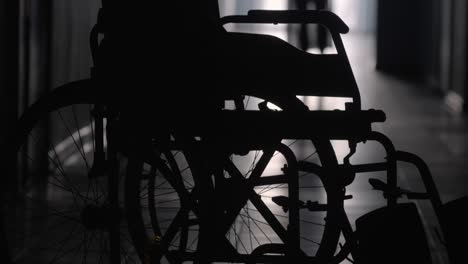 Silhouette-of-Woman-Limping-to-Wheelchair-along-Hospital-Hallway