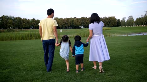 Familia-asiática-cogidos-de-la-mano-y-caminando-al-aire-libre