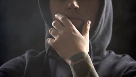 Dangerous-gangster-sitting-in-dark-room-full-of-smoke-and-planning-crime-closeup