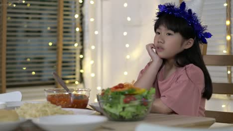 Asian-kids-girl-waiting-father-and-mother-coming-home-birthday-party-and-dinner-together.-Unhappy-family-time-at-home.-Concept-of-lonely,-disappointed-and-sad.