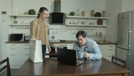 Wife-scolding-husband-gaming-on-laptop-in-kitchen