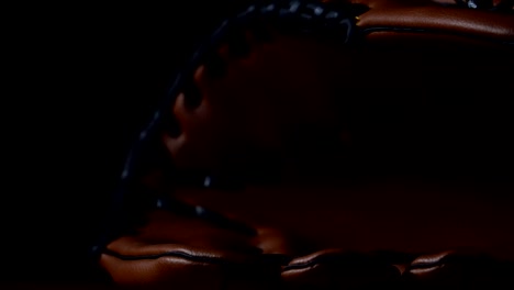 Werfen-Sie-einen-Baseball-mit-einem-Baseballhandschuh,-in-ein-dunkles-Licht-gelegt