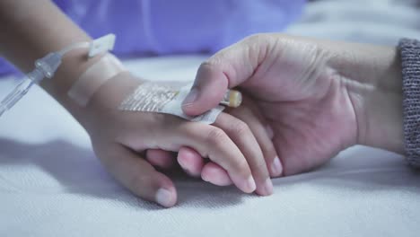 Mother-holding-hand-of-his-son-sick-bed-in-the-hospital.-Touch-the-hand-Slow-motion.-care-encouragement