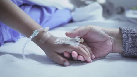 Mother-holding-hand-of-his-son-sick-bed-in-the-hospital.-Touch-the-hand-Slow-motion.-care-encouragement