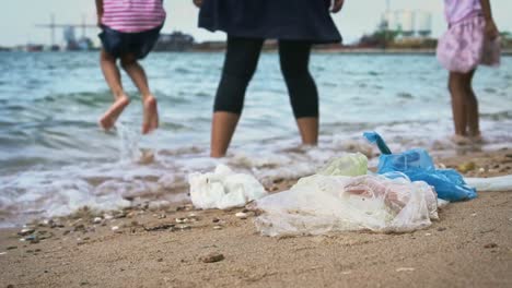 Plastikmüll-und-Müll-mit-Mutter-und-Tochter-spielen-am-Strand