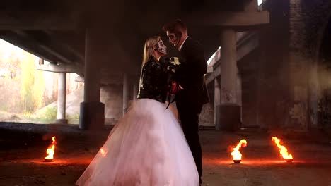 Pareja-en-vestidos-de-novia-con-maquillaje-de-Halloween-con-fuego-ardiendo-a-su-alrededor.