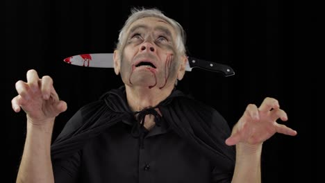 Elderly-man-with-knife-in-head.-Halloween-makeup-and-costume.-Blood-on-his-face