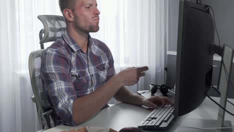 Hombre-guapo-disfrutando-de-pizza-sabrosa-mientras-trabaja-en-una-computadora