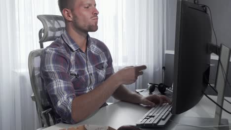 Handsome-man-enjoying-tasty-pizza-while-working-on-a-computer