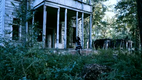 Halloween.-Eine-junge-Frau-mit-Einem-Skelettschmaus,-die-an-einem-Holzhaus-entlanggeht.-4K