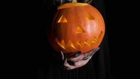 Halloween-Bild.-Junge-Hexe-in-schwarzer-Kleidung-hält-Kürbis-in-ihren-Händen.