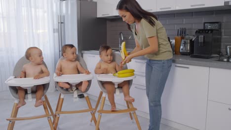 Asiatische-Mutter-geben-Bananen-zu-Kleinkind-Triplets