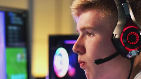 Teenage-Boy-tragen-Headset-Essen-Kartoffelchips-beim-Spielen-zu-Hause-mit-Dual-Computer-Bildschirme