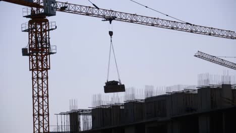 Turmkran-auf-einer-Baustelle-hebt-eine-Last-im-Hochhaus