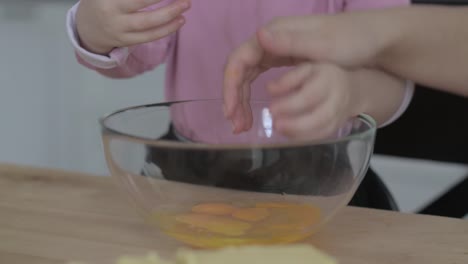 Little-girl-breaks-eggs-in-a-bowl-for-making-cookie-dough