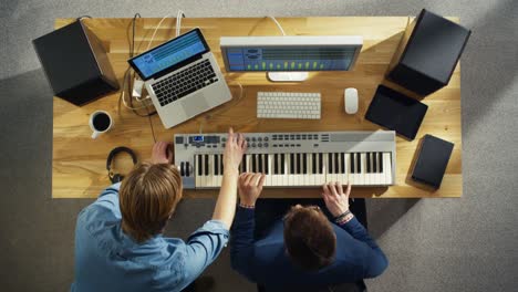 Top-View-of-Two-Audio-Engineers-Working-in-Their-Sunny-Studio.-They-Play-on-a-Musical-Keyboard-and-Experiment-with-Sound.