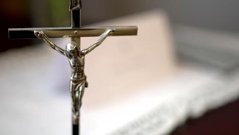 Metall-Kruzifix-mit-Heiligen-Schrift-verschwommen-im-Hintergrund