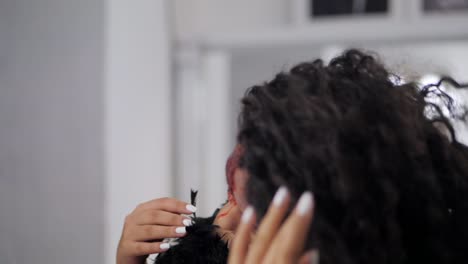 Scary-portrait-of-young-girl-with-Halloween-blood-makeup.-Beautiful-latin-woman-puts-the-curly-hair-down-near-mirror-in-the-dressing-room.-Slow-motion