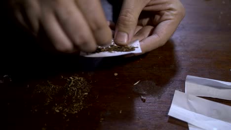 Close-up-male-hands-rolling-marijuana-cigarette