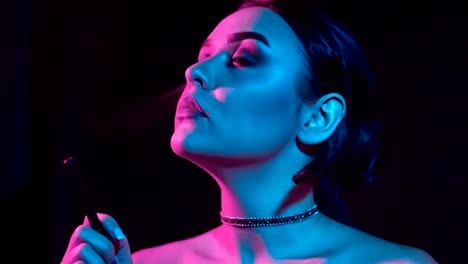 Gorgeous-brunette-woman-smoking-electronic-cigarette-in-neon-color-light