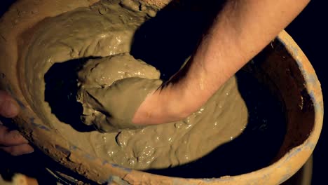 A-close-up-on-a-potters-hand-mixing-wet-clay.