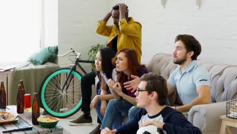 Slow-motion-of-Young-friends-watching-football-game-on-TV-together-at-home-and-disappointed-about-their-favourite-team-losing-match