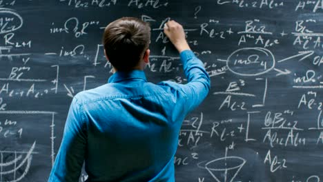 Brilliant-Young-Mathematician-Approaches-Big-Blackboard-and-Finishes-writing-Formula,-Turns-Around-and-Smiles-on-Camera.