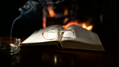 Open-book-on-table-in-front-of-burning-fireplace