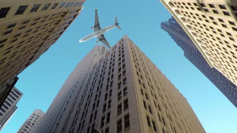 BOTTOM-UP:-Große-kommerzielle-Flugzeug-fliegt-niedrig-und-in-der-Nähe-von-hohen-Wolkenkratzern.