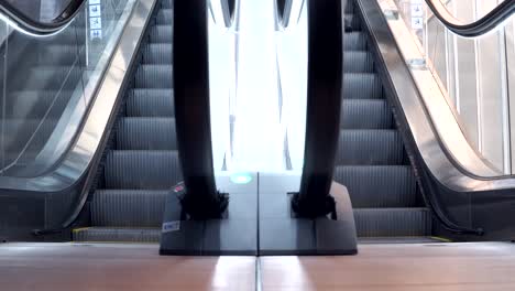 Young-man-walking-down-from-modern-escalator-stairs.-Moving-staircase-running-up-and-down.-urban-lifestyle-concept.