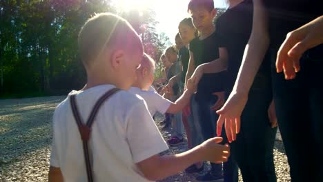 Adolescentes-y-niños-equipos-saludándose-con-estrechan-la-mano-en-el-día-soleado-de-verano