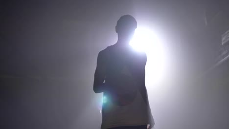 One-basketball-player-silhouette-practicing-and-throwing-ball-in-hoop-indoors