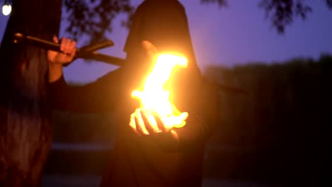 Vestido-de-brujo-misterioso-en-una-capa-con-un-hombre-de-fuego-en-la-fantasía-medieval.-Halloween