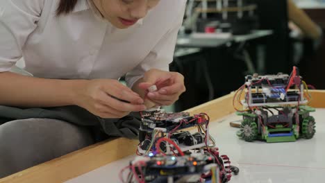 Ingeniero-electrónico-mujer-trabaja-con-el-robot,-construcción,-fijación-de-robótica-en-el-taller.-Personas-con-el-concepto-de-tecnología-o-innovación.