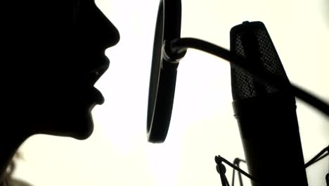 Silhouette-of-a-woman-singing-a-song-in-a-recording-studio