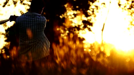 Men's-baseball-practice-hitting-a-baseball-with-the-light-of-sunset