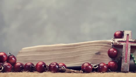 Open-Bible-and-the-crucifix-beads-on-a-golden-table,-close-up.-Beautiful-dark-background.-Religion-concept