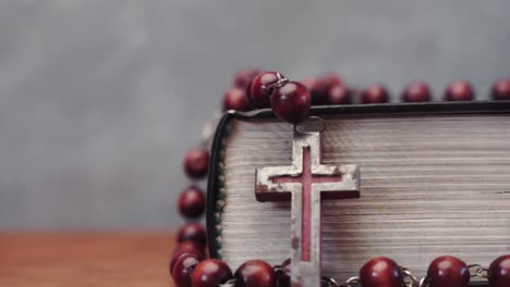 Bible-and-the-crucifix-beads-on-a-red-wooden-table.-Beautiful-background.-Religion-concept-close-up