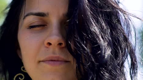 Woman-with-dark-hair-meditates-with-closed-eyes-outdoors,-inner-temple-oneness