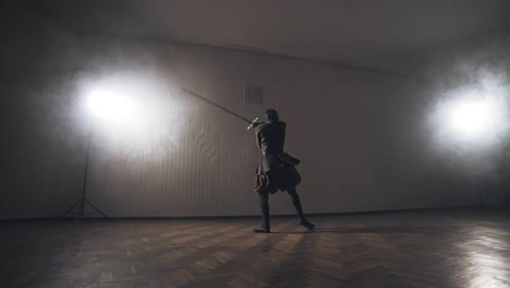 Medieval-warrior-training-with-two-handed-sword-indoors-in-slow-motion