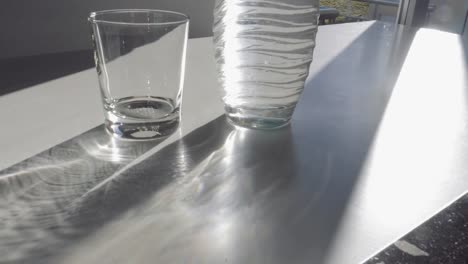 Volle-Wasserflasche,-leeren-Becher-und-Sonnenschein