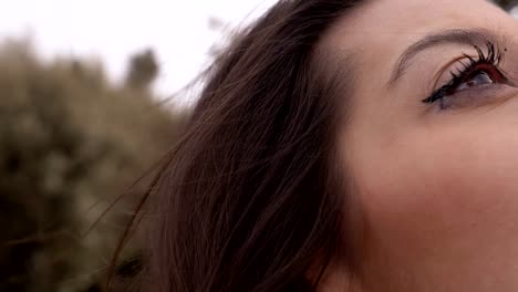 thoughtful-young-brunette-looking-up-in-the-park--slow-motion--half-face