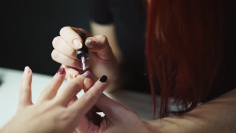 manicurista-es-a-uñas-de-la-pintura-de-una-mujer-en-un-salón-de-belleza-en-la-mesa.