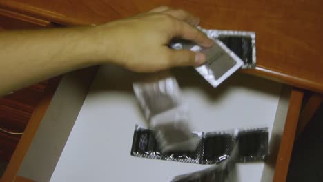 Man-puts-a-condom-into-the-bedside-table.