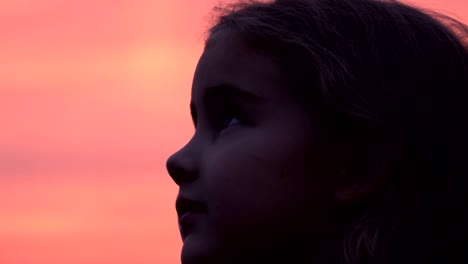 Kid-looking-up-at-the-sky-in-nature.-Little-girl-praying-looking-up-at-purple-sky-with-hope,-close-up.