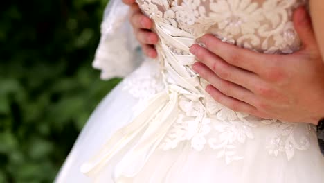 Close-up-of-the-groom-embracing-his-bride.-Rear-view.