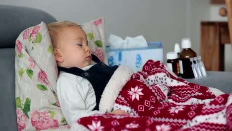 Sick-little-boy,-sleeping-covered-with-soft-blanket-on-the-couch-in-living-room,-medicine-next-to-him