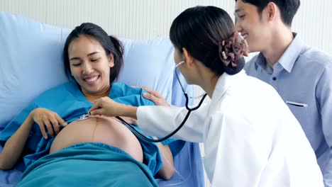 Female-doctor-visiting-to-pregnant-woman-at-hospital.-Pregnant-woman-and-he-husband-talking-to-doctor-with-happy-emotion.-People-with-healthcare-and-medical-concept.