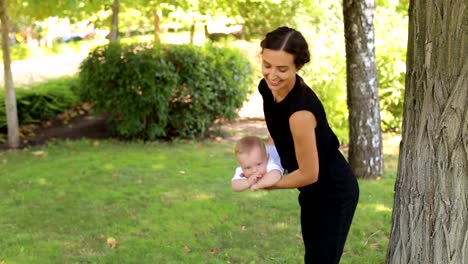 Eine-junge-glückliche-Mutter-geht-mit-ihrem-neugeborenen-Sohn-im-Park-im-Sommer.