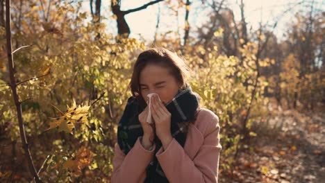 Junge-kranke-Frau-steht-Niesen-im-Park-in-Herbsttag,-mit-Taschentuch